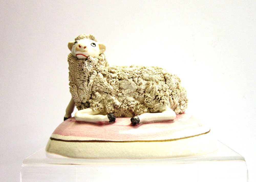 An early 19th Century Staffordshire model of a recumbent Sheep on an oval plinth base, 14 cms wide