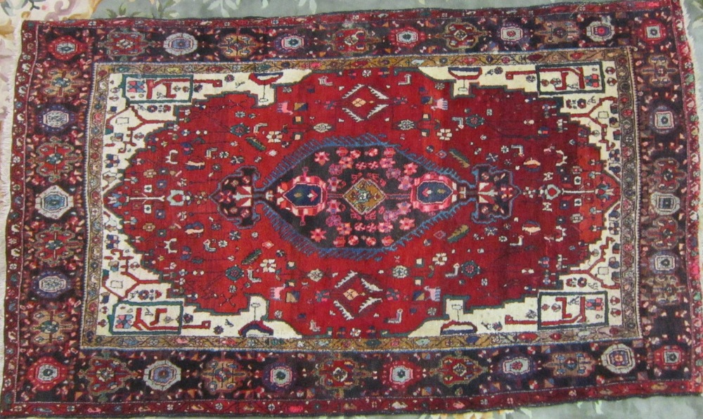 A Persian Hamadan Rug on a red ground, 221 x 128 cms