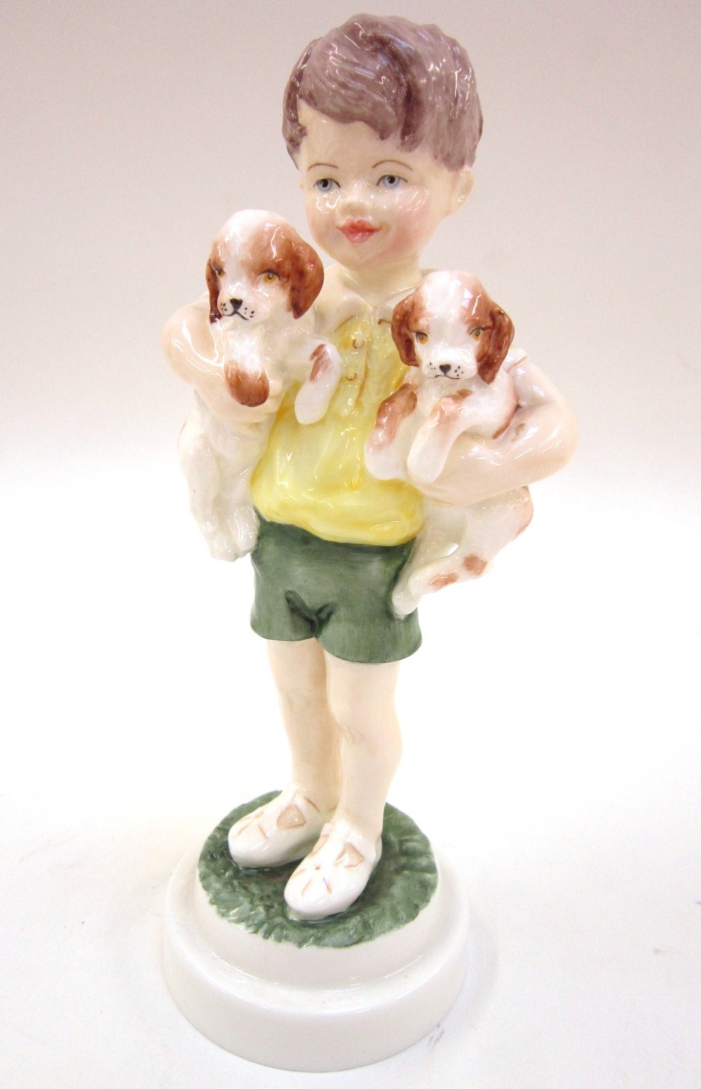 A Royal Worcester Figure `All Mine`. No. 3519 of a young boy holding a puppy in each arm, modelled