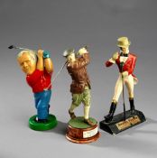 Three golfing figurines, a Johnnie Walker advertisement figure holding a golf club, left leg broken,