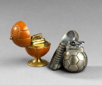 Two table cigarette lighters with football designs, one with a hinged football opening to reveal