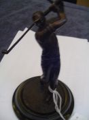 A modern bronze figure of a golfer, modelled in the follow through position, on a circular base,