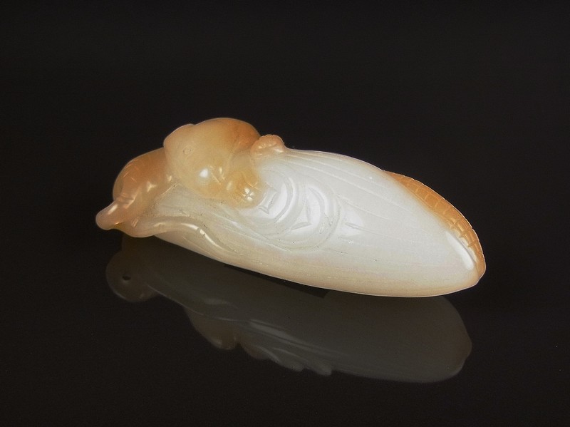A Chinese jadite pedant carved as a cob of corn with rodent. The stone of a translucent white and