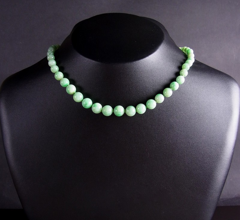 Graduated jade necklace. Set with fifty seven graduated green jade beads individually knotted to a