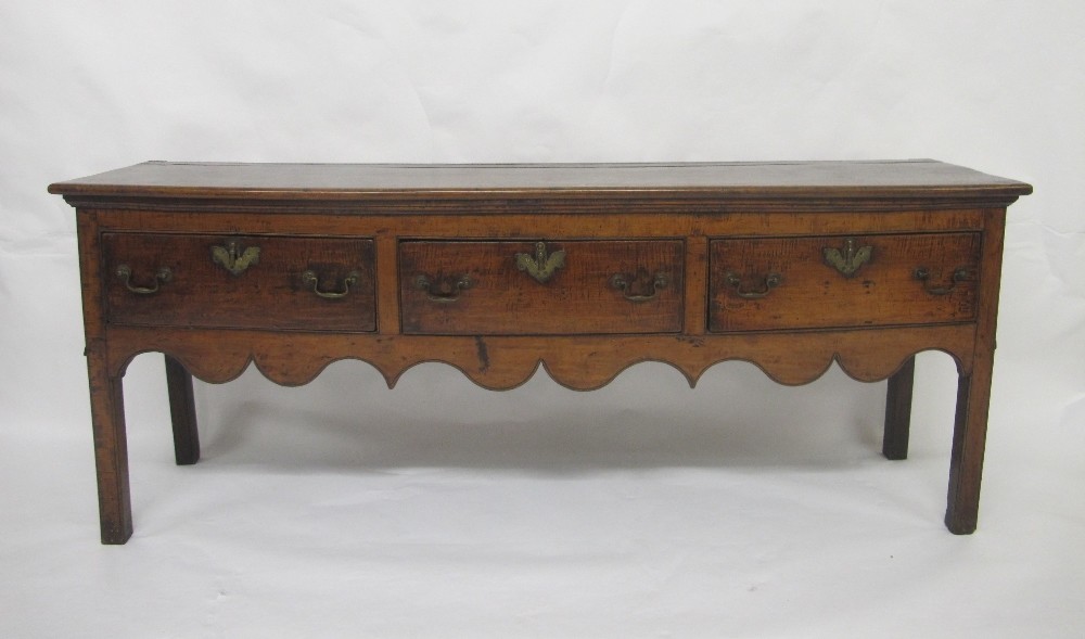 A George III mahogany dresser with three drawers above a shaped apron, and raised on plain supports,