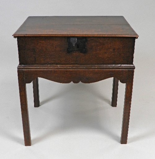 A 18th century oak bible box on stand, the hinged lid over a central iron lock plate and wavy frieze