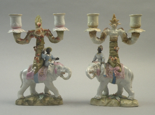 A pair of Pössneck porcelain candelbra, late 19th century, modelled as Arabian figures seated atop