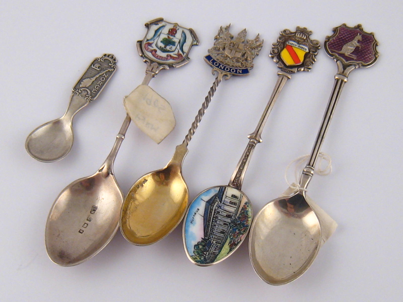 A group of five souvenir teaspoons, four enamelled.