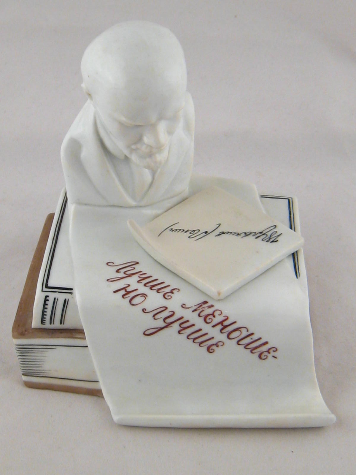 An early Soviet Russian ceramic inkwell in the form of a bust of Lenin atop a scroll and books , the