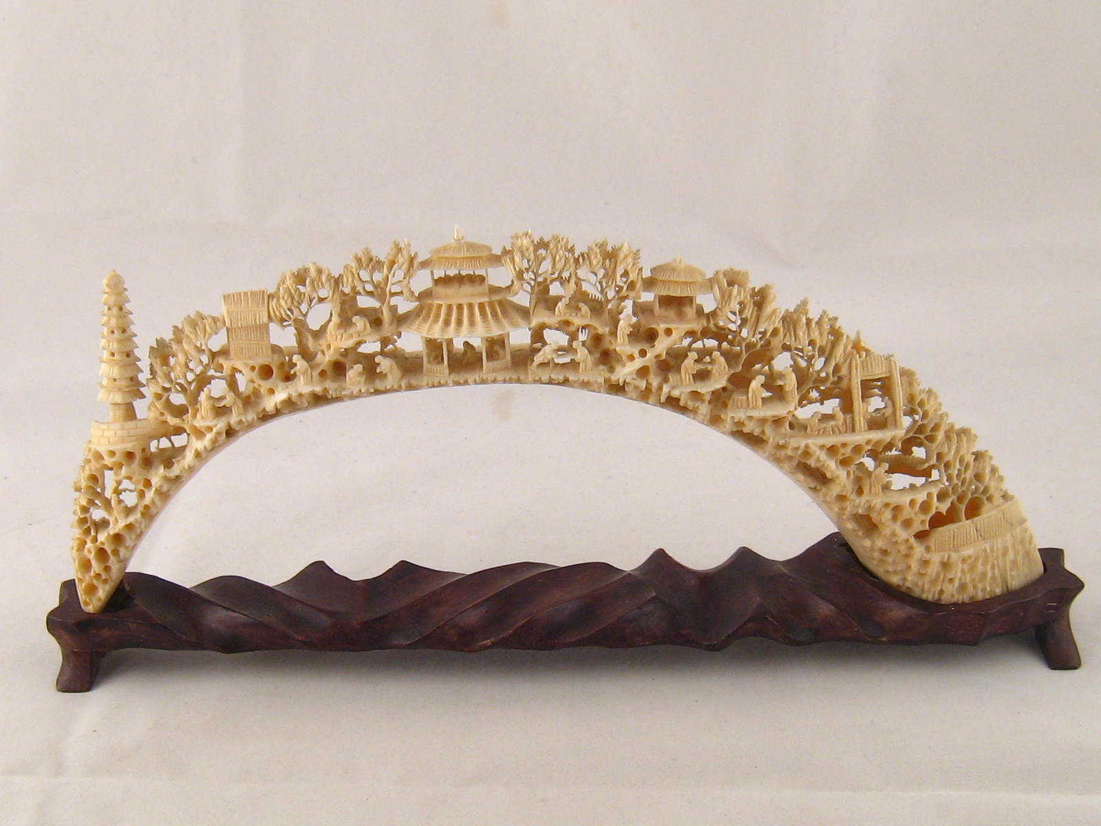A Chinese ivory tusk exceptionally finely carved with figures and buildings in succeeding