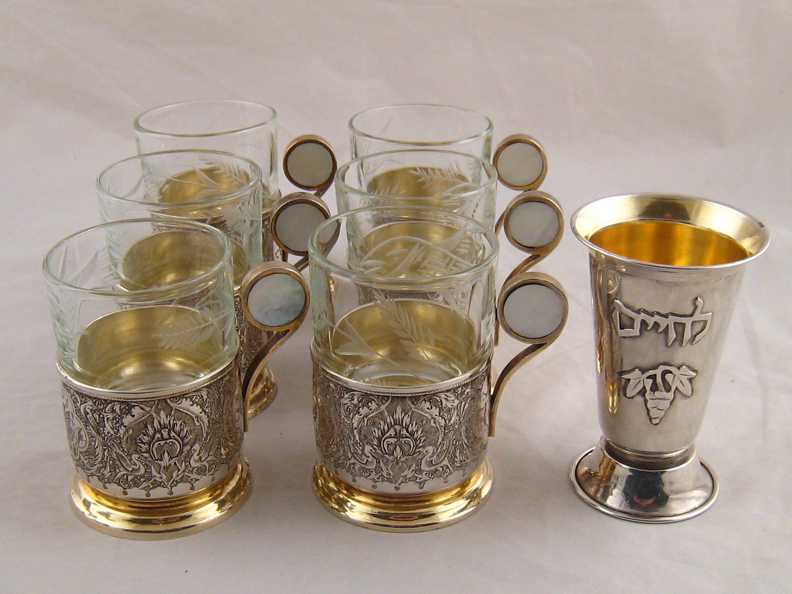 A set of six tea glasses, the Iranian assayed silver holders with m.o.p. insets, together with a