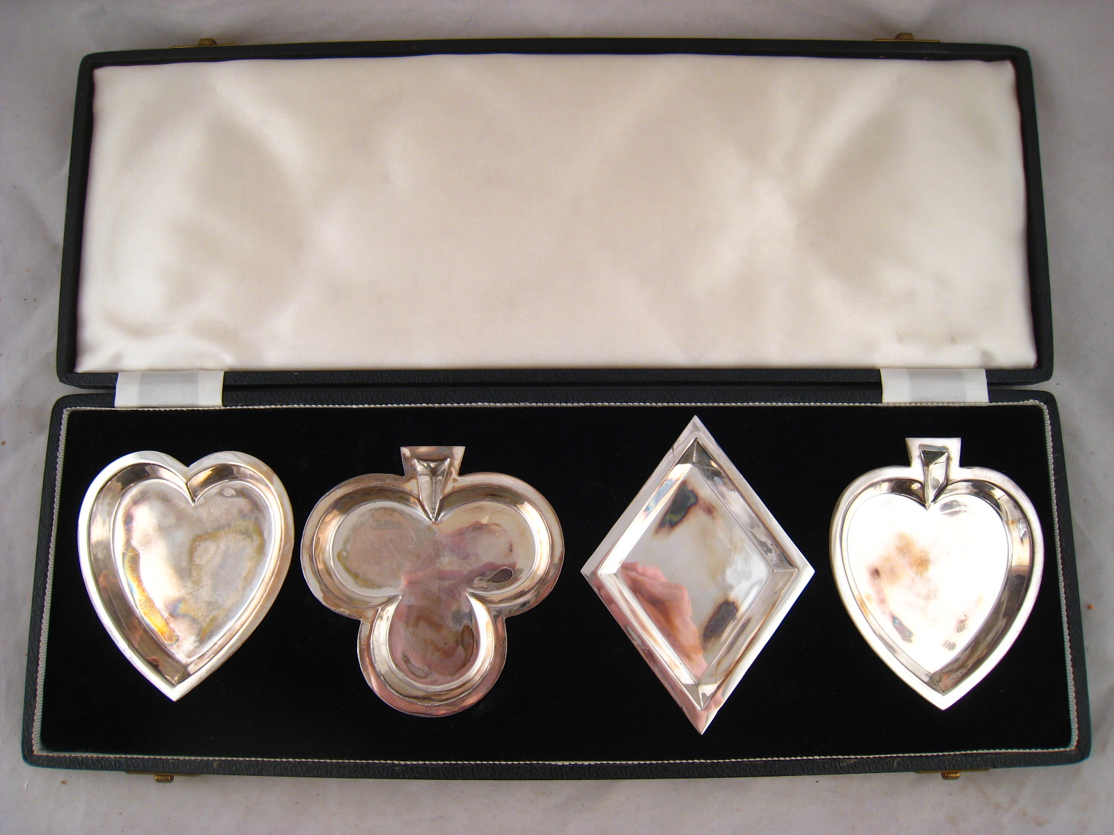 A boxed set of four silver bridge dishes, each in the form of a card suit. by James Dixon and