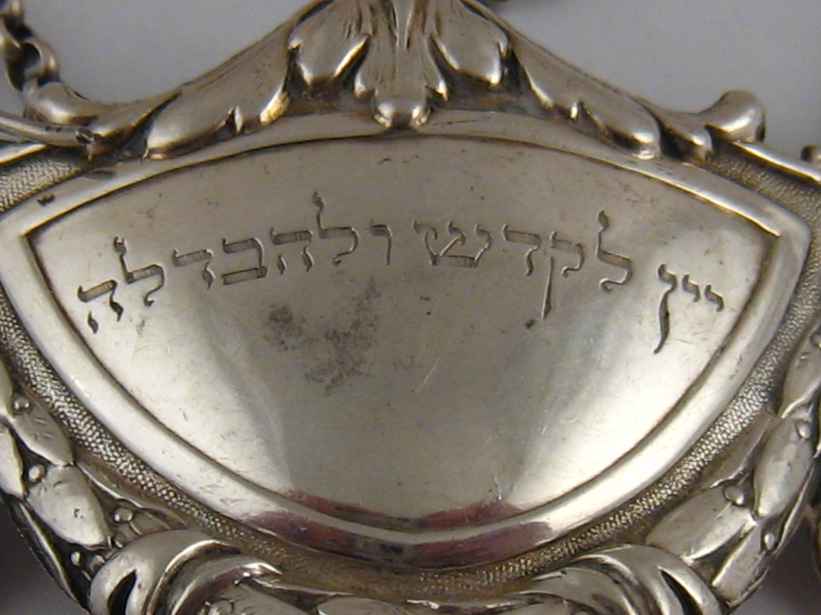 Judaica. A silver, German 800 assay, wine label of unusual shield and swag design, c. 1930, with