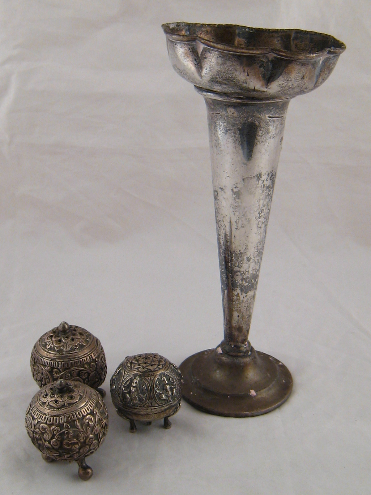 A matched three piece white metal, (two test silver), Indian condiment set and a silver vase,(AF)