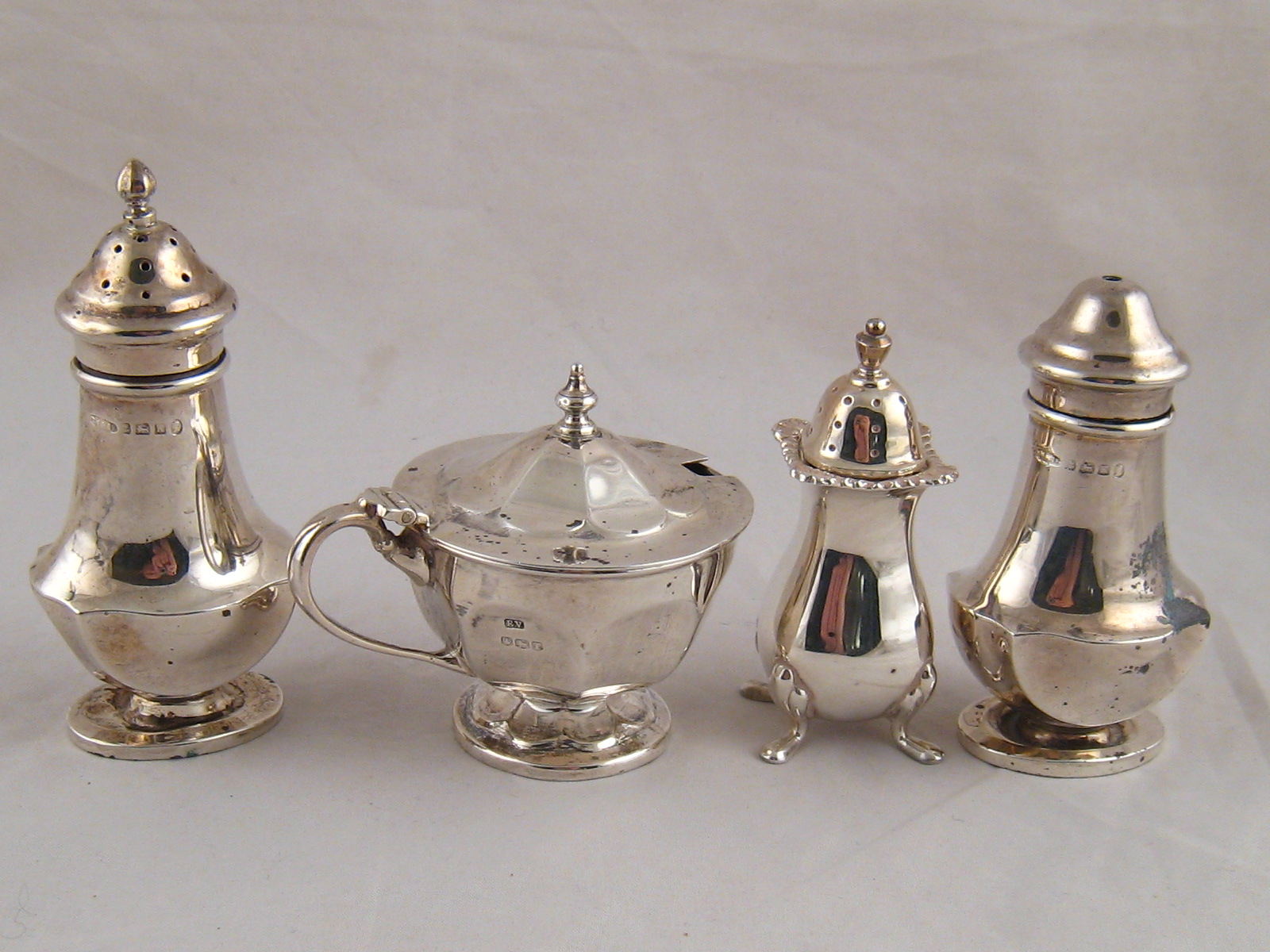 A silver three piece cruet set and an additional pepper.wt. 198g.