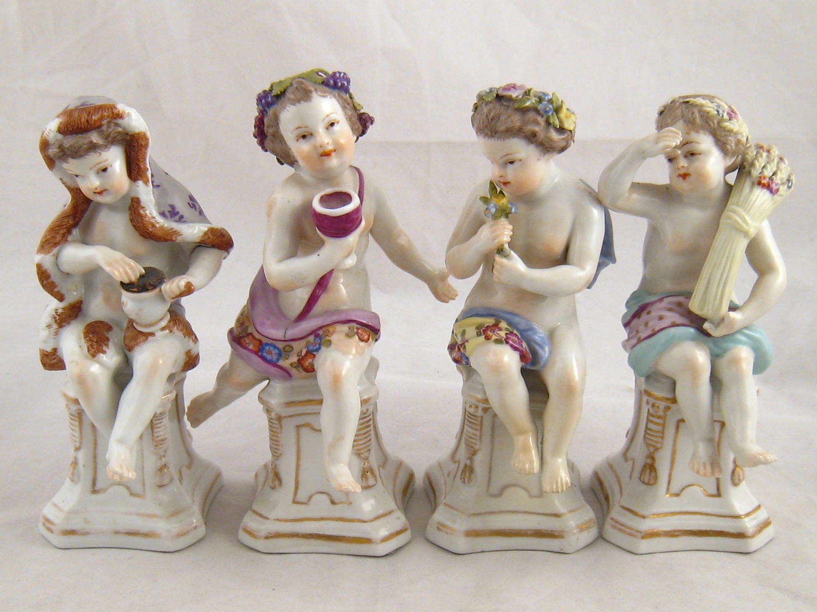 A set of four porcelain figures representing the four seasons, each with underglaze AR monogram.