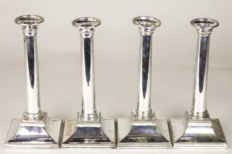 A matched set of four Georgian plated candlesticks with plain columns on sloping square bases, 25.