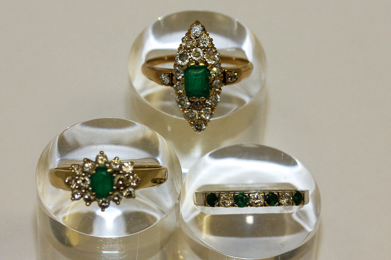 An emerald and diamond cluster ring; an emerald and diamond half hoop eternity ring and a marquise