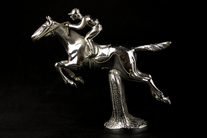 Le Jeune, a chrome car mascot of a horse and jockey going over a hurdle, stamped Le Jeune Made in
