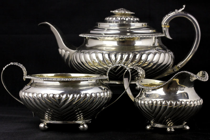 A George IV matched silver three piece tea set, London 1824 and 1826, with half reeded, whorled