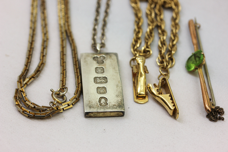 A peridot bar brooch; a silver ingot pendant; a gilt cloak chain and a silver gilt longchain