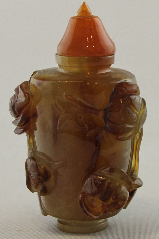 A Chinese amber/brown `jade` snuff bottle carved with flowers and leaves, 9cm high