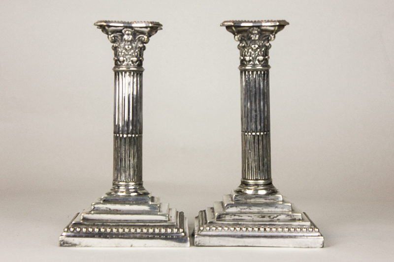 A pair of Corinthian column plated candlesticks on square stepped bases, 22cm high