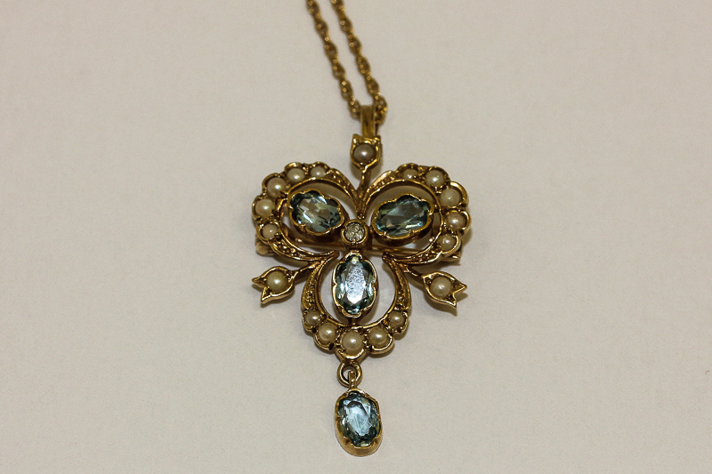 A 9ct gold aquamarine and split pearl pendant, trefoil shape and hung with an oval cut stone