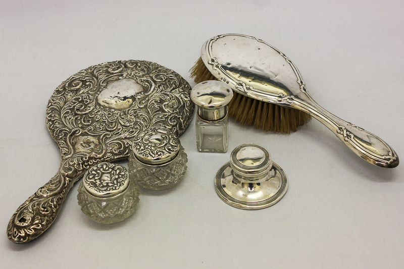 A silver back hand mirror (af); a silver back hair brush; a silver inkwell and three silver top