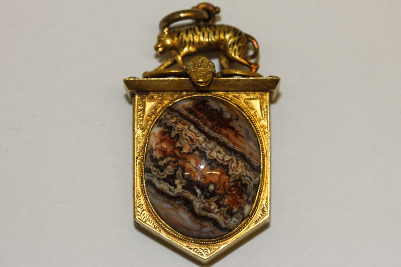 An 18ct gold shield shaped photograph `locket` with tiger and serpent mount and `agate` cabochon