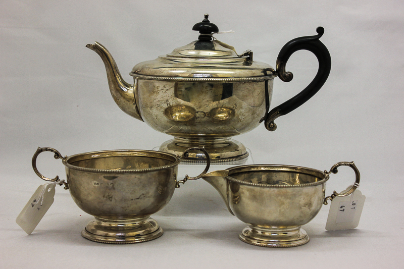 A three piece silver tea set, maker TS, Birmingham 1931 with circular bodies and scroll handles