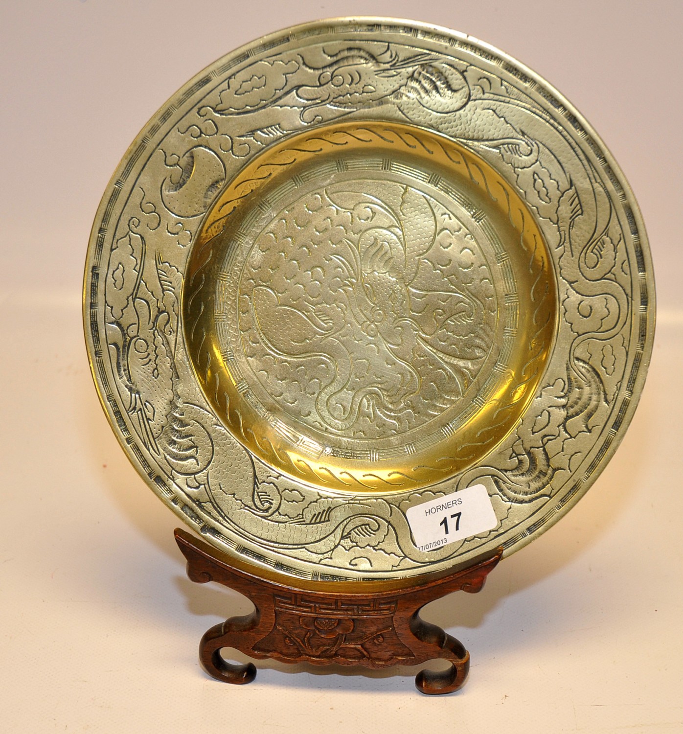 A HEAVY BRASS CHINESE PLATE WITH CHASED MYTHICAL FISH.  THE BACK STAMPED WITH CHINESE CHARACTERS.