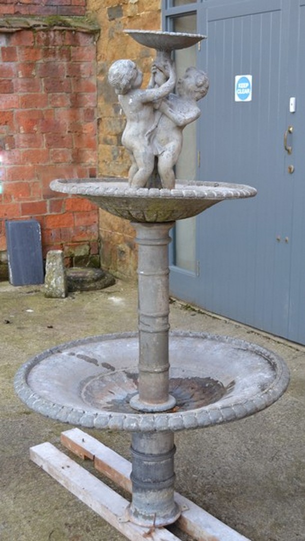 A three-tier lead figural garden fountain, 158cm (62in) high, together with a cast iron trough pump