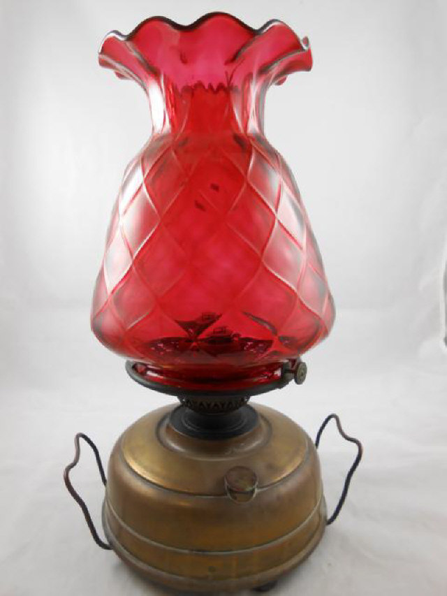 A late 19th/early 20th century oil lamp, cranberry glass shade with flared top, burner marked