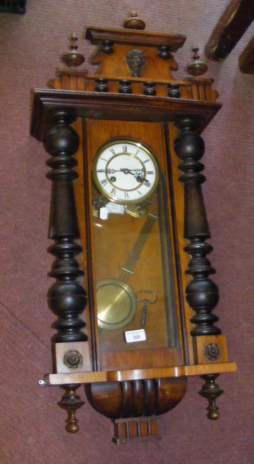 A mahogany cased Vienna style striking wall clock with visible pendulum