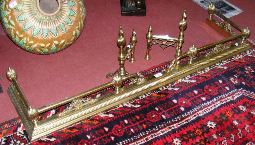 A decorative brass fire fender with dogs