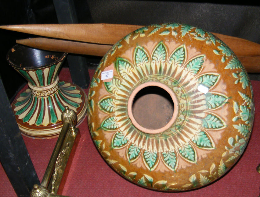 A pair of long carved ceremonial wooden spears, together with a terracotta vessel on stand