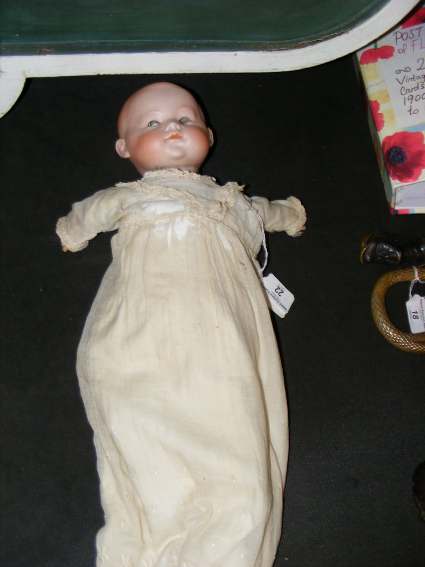 An antique bisque head doll with straw body