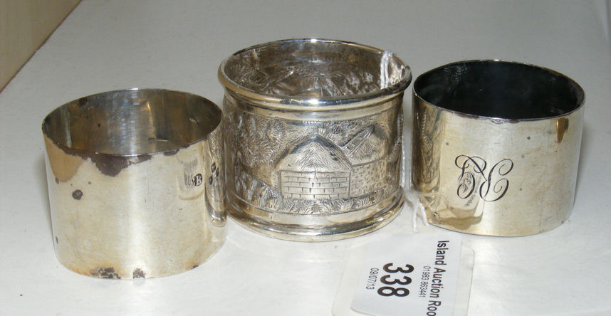 A pair of plain silver napkin rings and a chased and engraved Eastern ditto