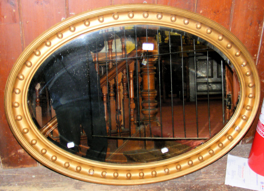 A 102cm x 72cm oval bevelled hanging wall mirror in gilt gesso frame