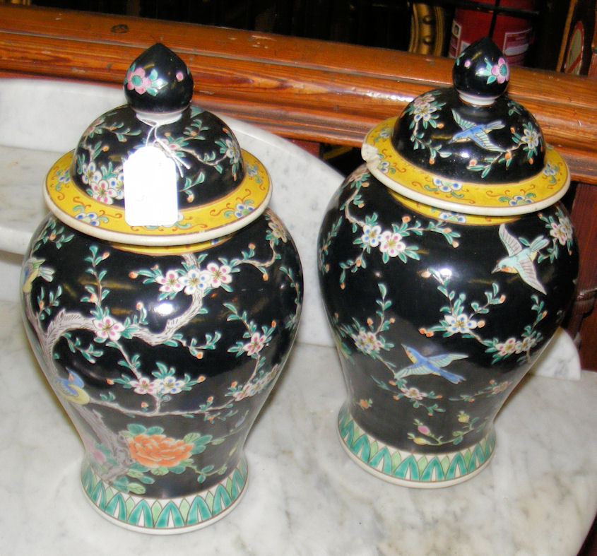 A pair of oriental baluster vases and covers with black ground Prunus and bird decoration