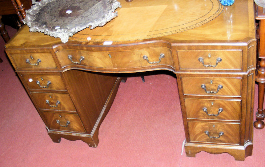 A walnut nine drawer kneehole desk with tooled inset leather top