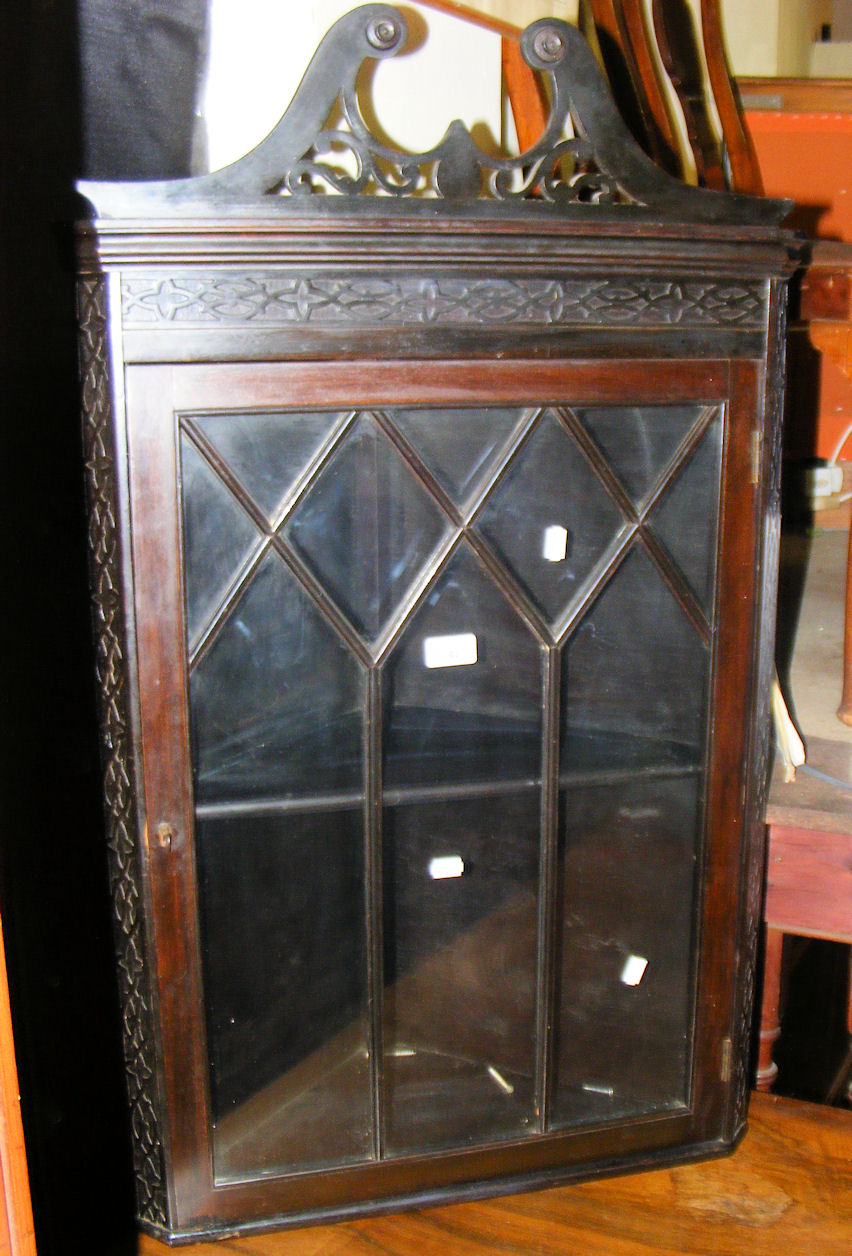 An ebonised hanging corner cabinet enclosed by a glazed and beaded door