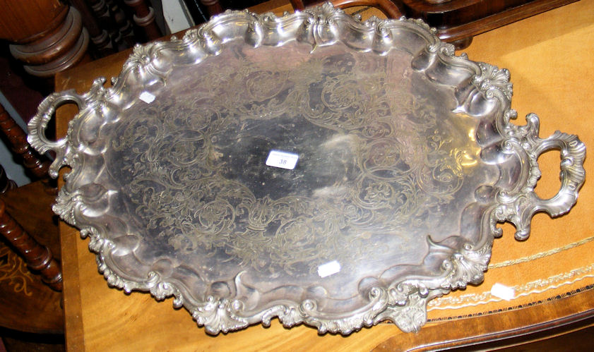 A large silver plated two handled serving tray with embossed surround and chased and engraved base