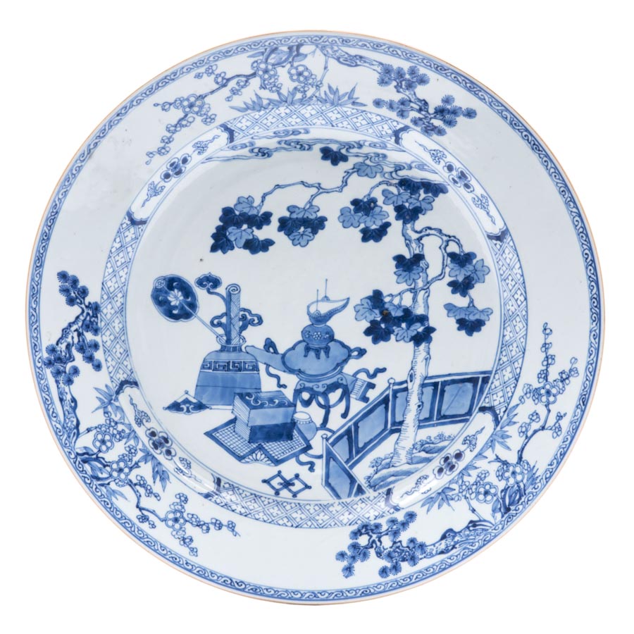 A Chinese blue and white porcelain dish, decorated to the well with a selection of scholarly objects