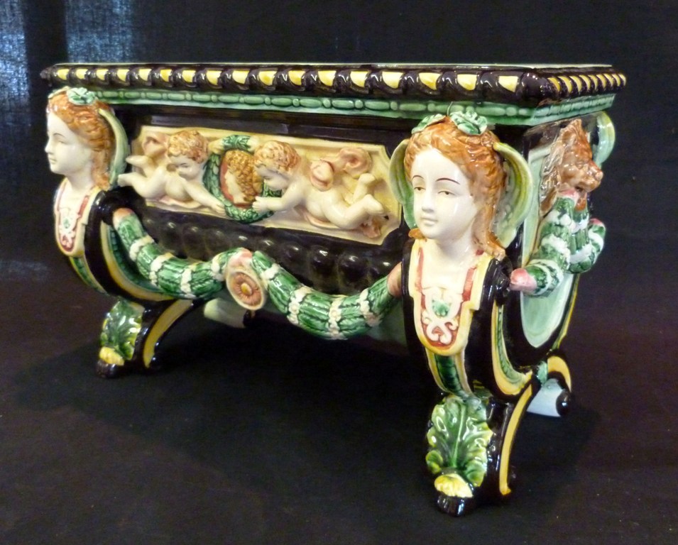 A Majolica Large Planter, decorated in relief with putti and figureheads upon shaped supports, 37cms