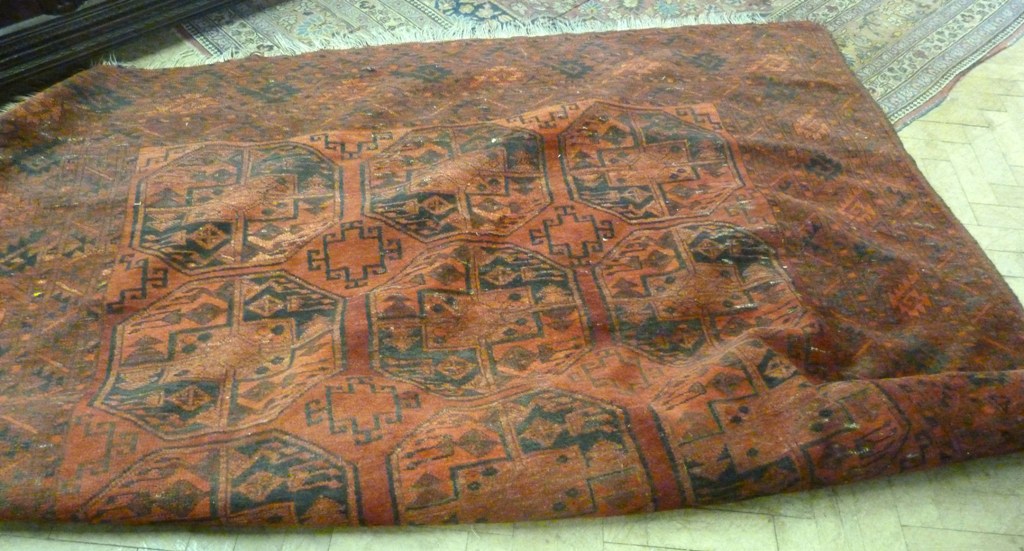 An Afghan Woollen Carpet, with allover design upon a red ground within multiple borders