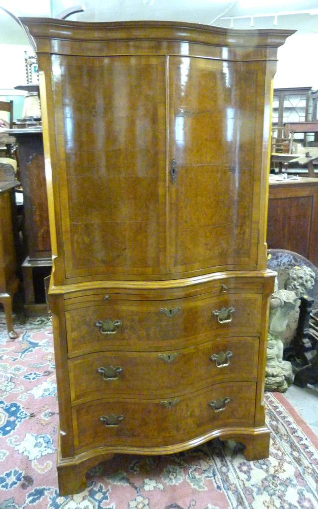 A Walnut Serpentine Cocktail Cabinet, with two doors above a brushing slide and three drawers with