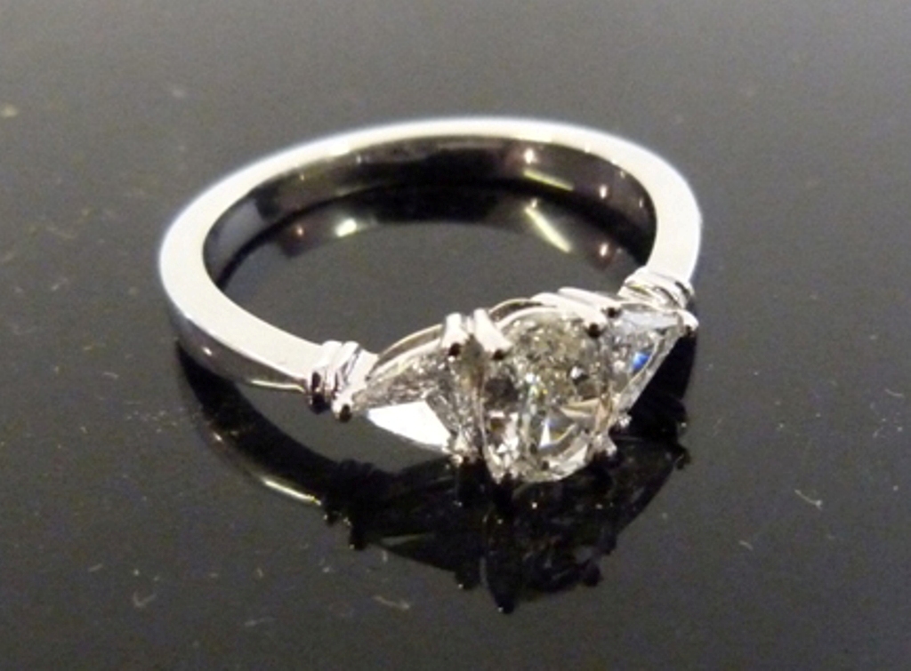 An 18ct White Gold Three Stone Diamond Ring, with a central oval diamond flanked by a diamond within