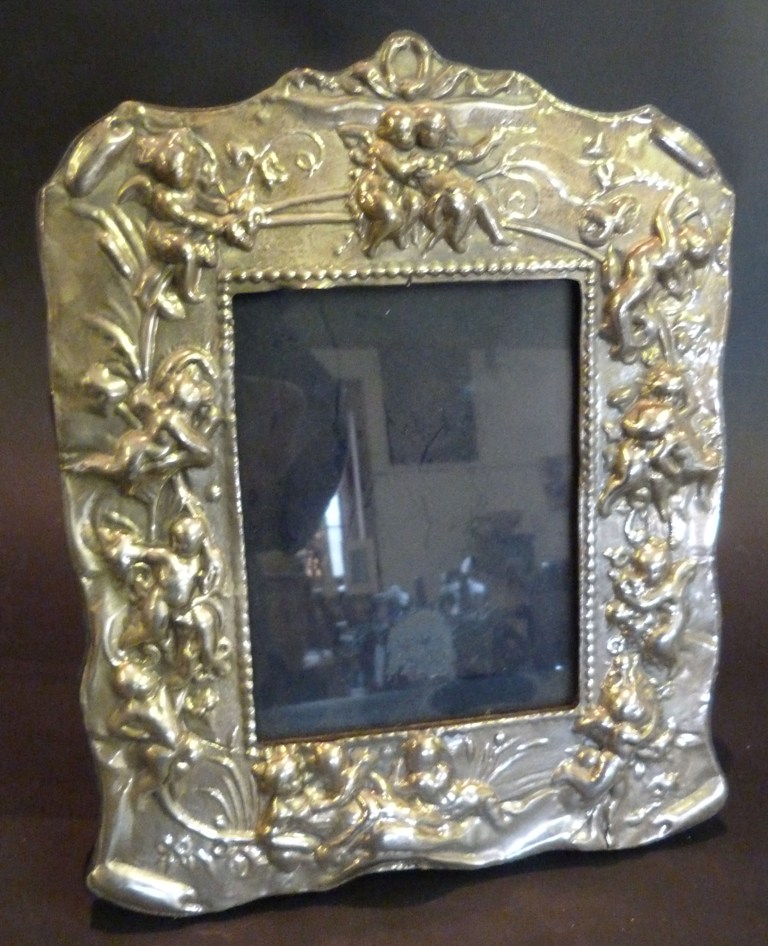 A Rectangular Silver Photograph Frame, embossed with putti amongst foliage, 22.5 x 18cms